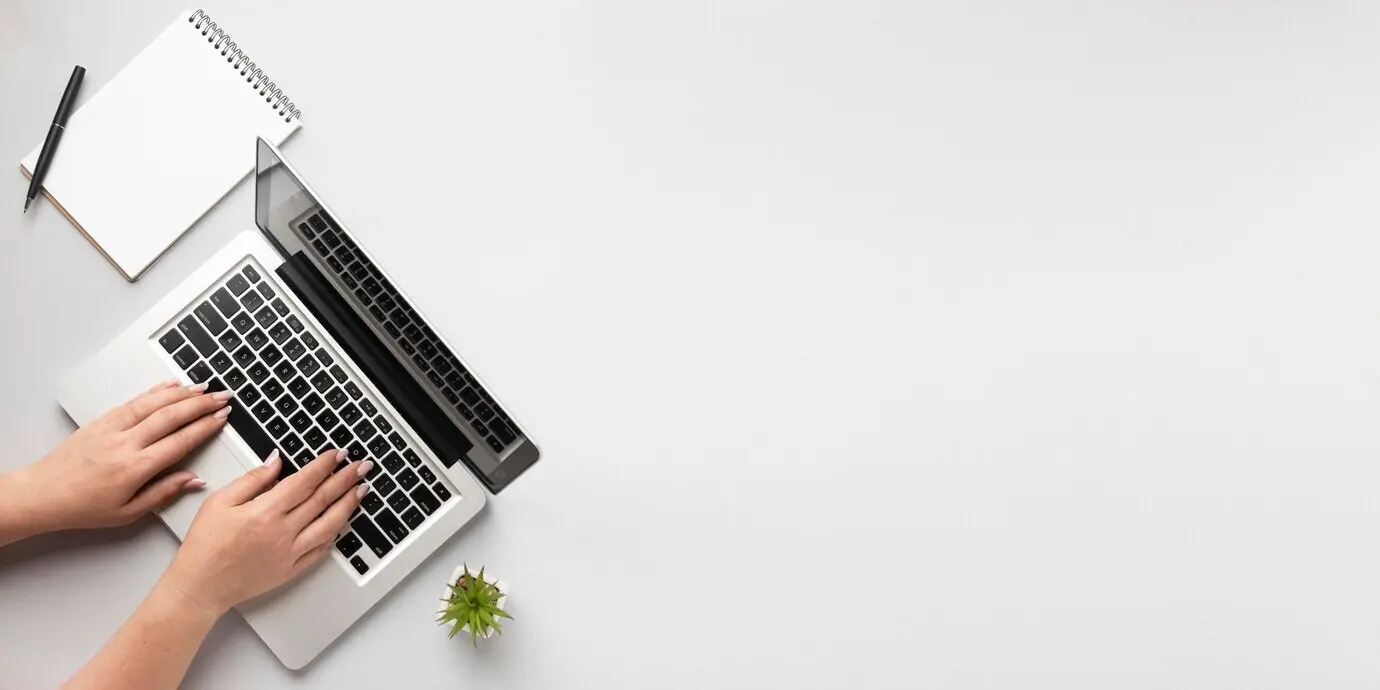 Ansicht von oben einer Person, die auf einem Laptop schreibt, mit Platz für Text.